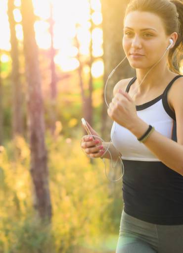 Frau joggt im Wald mit Sonnenlicht